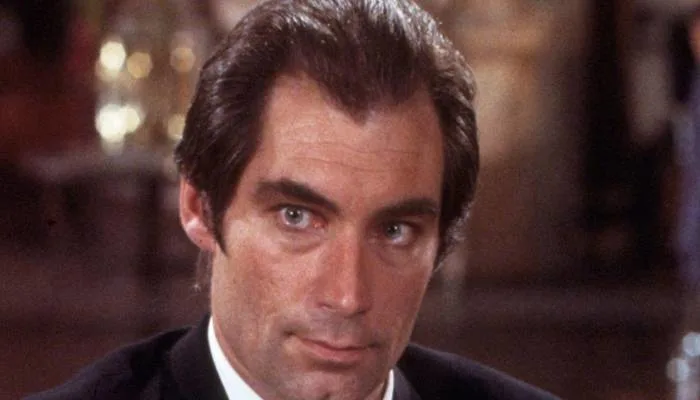 Timothy Dalton as James Bond looking serious in a classic trench coat